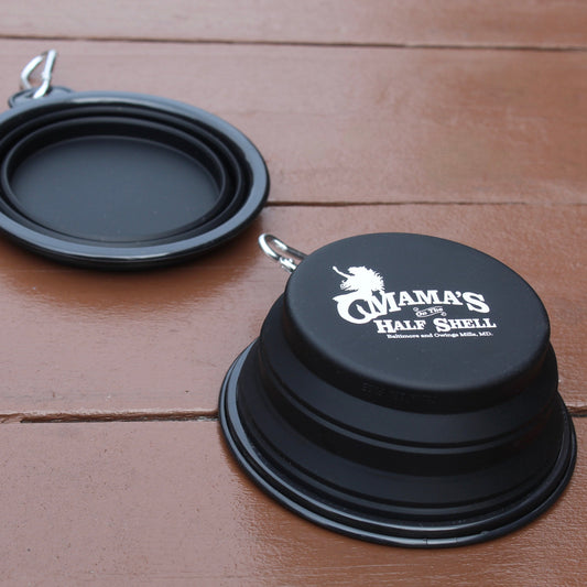 Black collapsible pet bowl with 'Mama's On The Half Shell' branding on a wooden surface